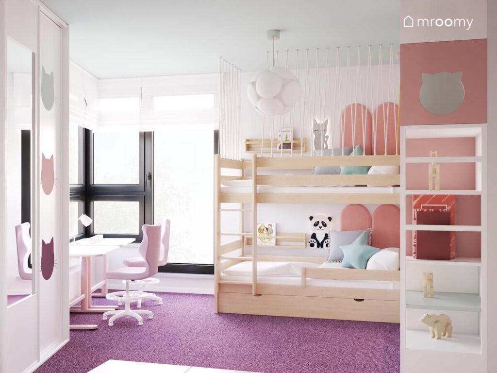 Jasny pokój dla dwóch dziewczynek a w nim drewniane łóżko piętrowe białe meble oraz kocie dodatki