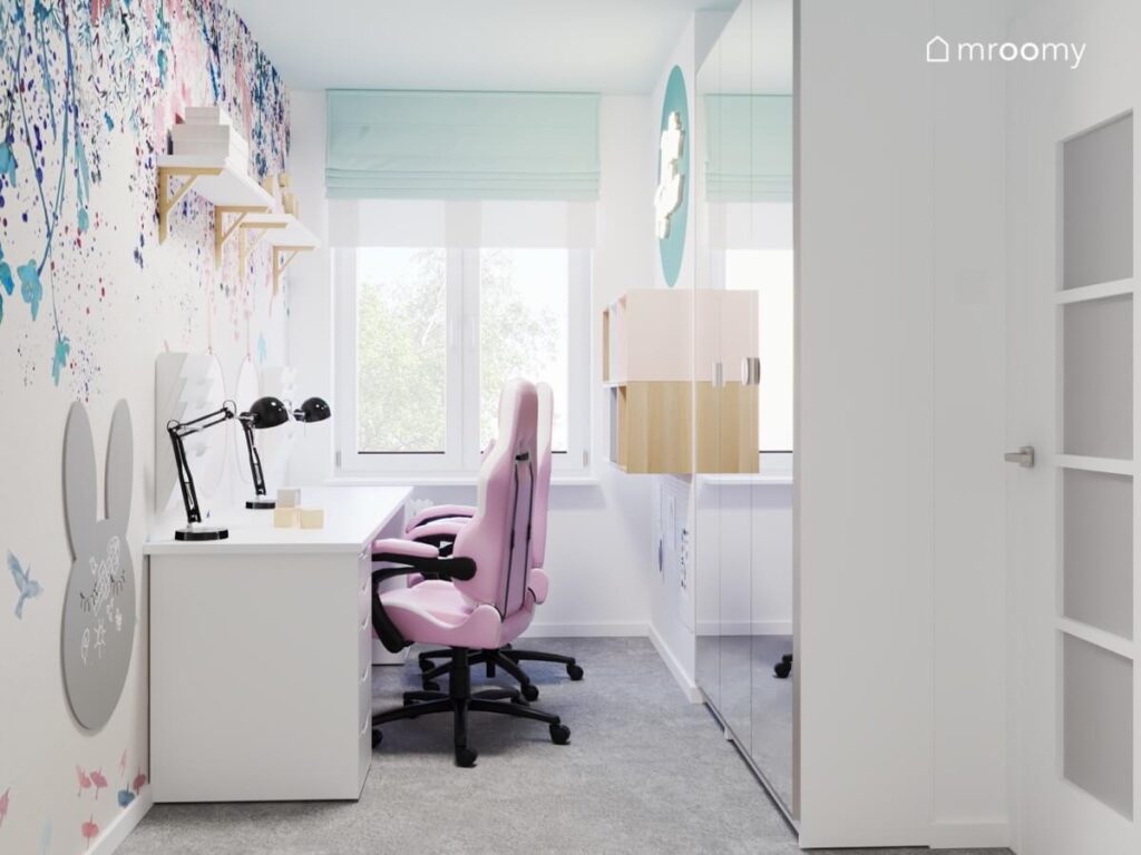 Jasny pokój dla dwóch dziewczynek a w nim strefa nauki z różowymi fotelami oraz duża szafa z lustrzanym frontem