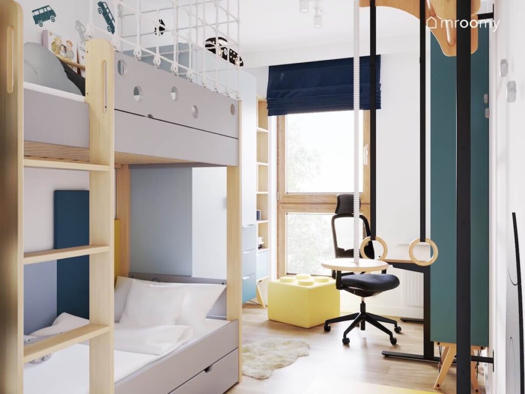 Jasny pokój dla małego chłopca a w nim łóżko piętrowe pufka w kształcie klocka oraz drabinka gimnastyczna