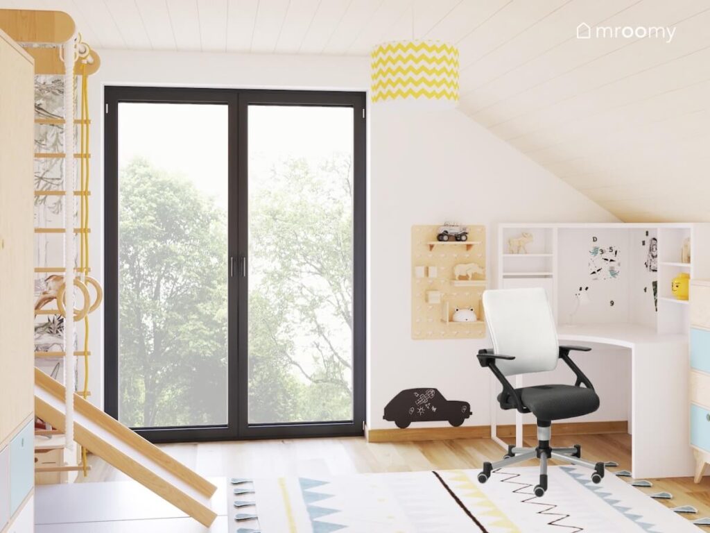 Jasny poddaszowy pokój dla pięciolatka a w nim białe biurko z organizerami oraz wzorzysty dywan