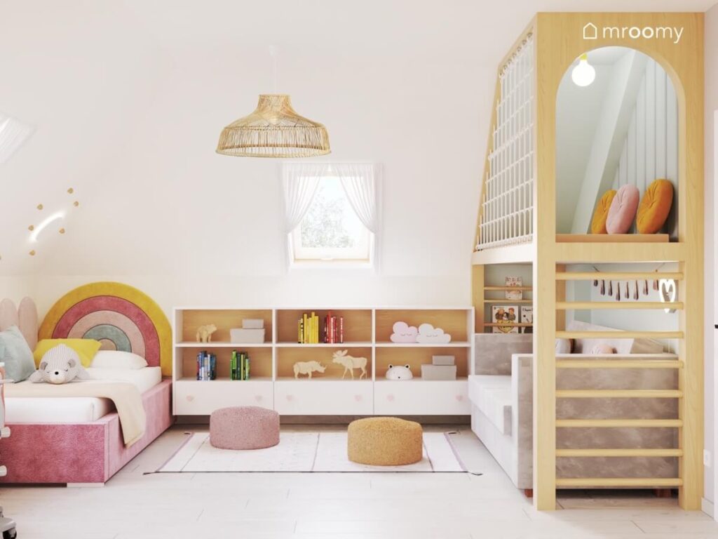 Biały poddaszowy pokój dla pięciolatki a w nim różowe tapicerowane łóżku niskie szafki pufki oraz antresola z miejscem do zabawy i kanapą pod spodem