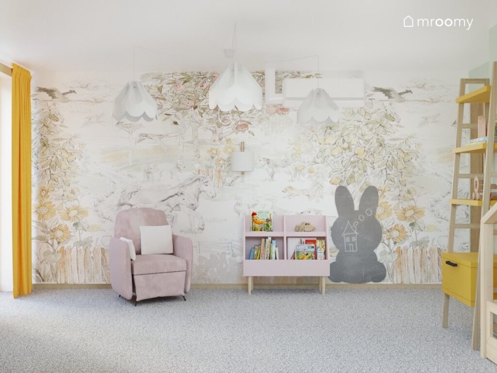 Ściana pokryta malowniczą tapetą z końmi a na niej tablica kredowa w kształcie królika biblioteczka kinkiet oraz jasny fotel w pokoju dziewczynki