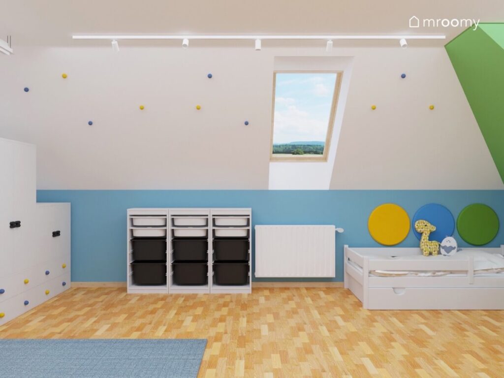 Biało niebiesko zielony pokój dla sześciolatka a w nim białe łóżko regał z pojemnikami a na skosie ozdobne żółte i niebieskie gałki