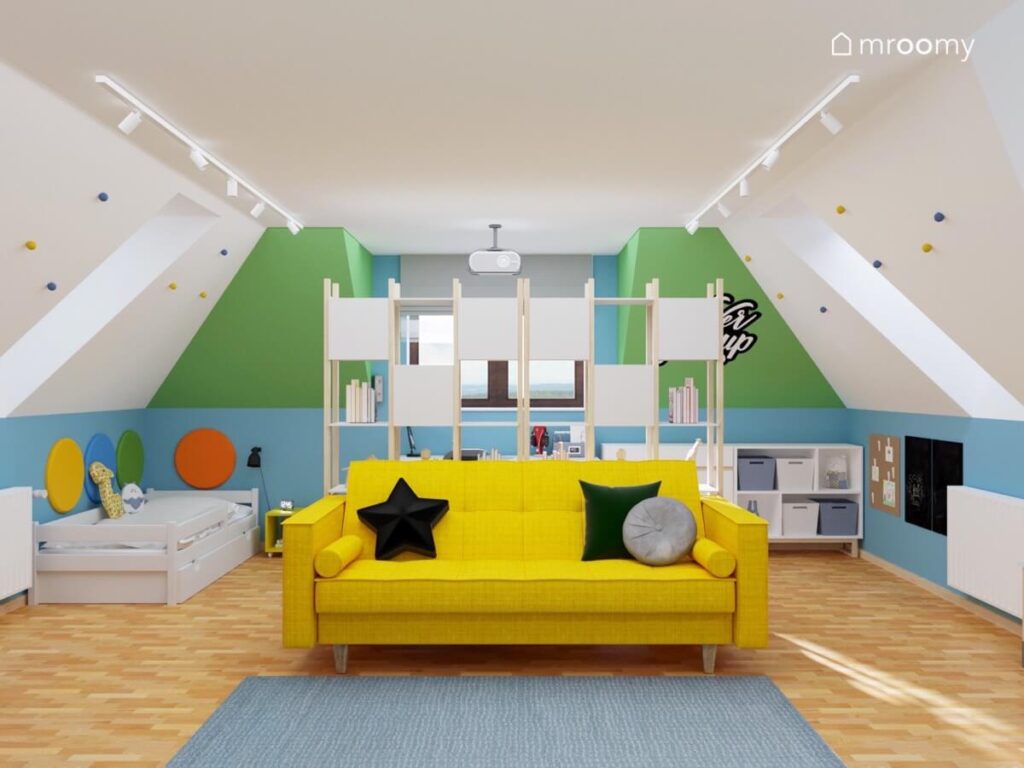 Przestronny kolorowy pokój dla chłopca na poddaszu a w nim biało zielono niebieskie ściany żółta sofa oraz duży biało drewniany regał