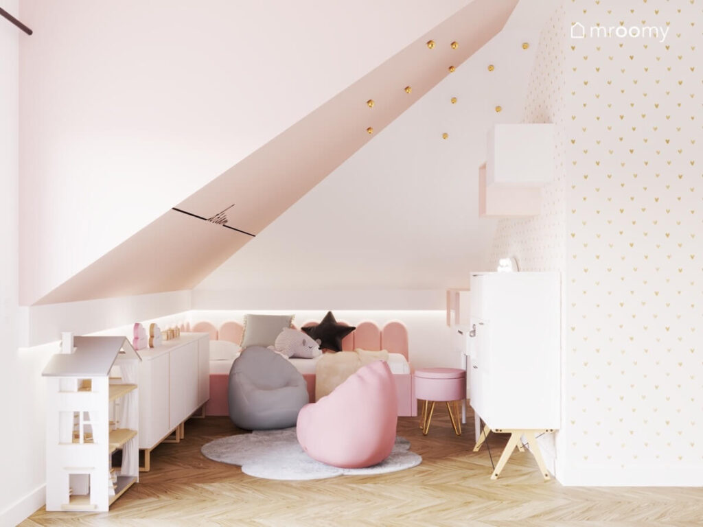 Strefa spania w poddaszowym pokoju dziewczynki a w niej różowe tapicerowane łóżko a obok pufy do siedzenia