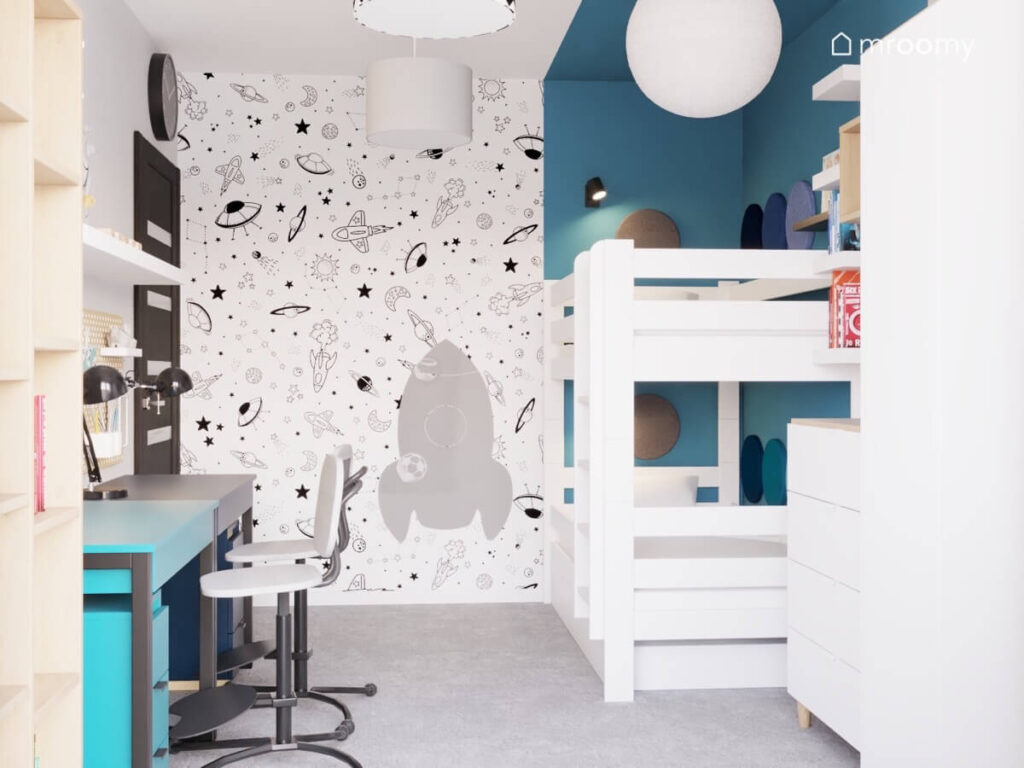 Biało niebieski pokój dwóch braci a w nim białe łóżko piętrowe kosmiczna tapeta na ścianie oraz tablica kredowa w kształcie rakiety