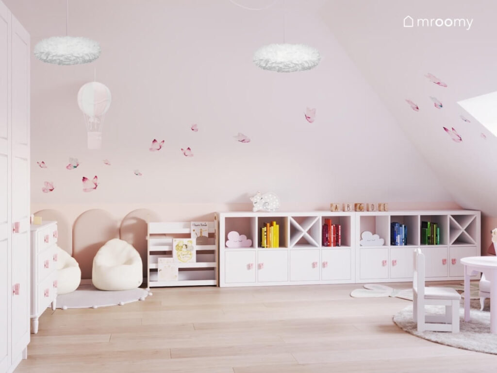 Poddaszowy pokój malutkiej dziewczynki z białymi meblami z gałkami w kształcie królików lampami z piór oraz naklejkami w kształcie motyli na ścianach