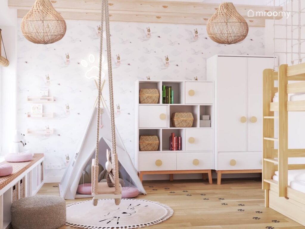 Namiot tipi huśtawka wisząca białe meble z drewnianymi uchwytami a na ścianie tapeta w łabędzie w pokoju dwulatki