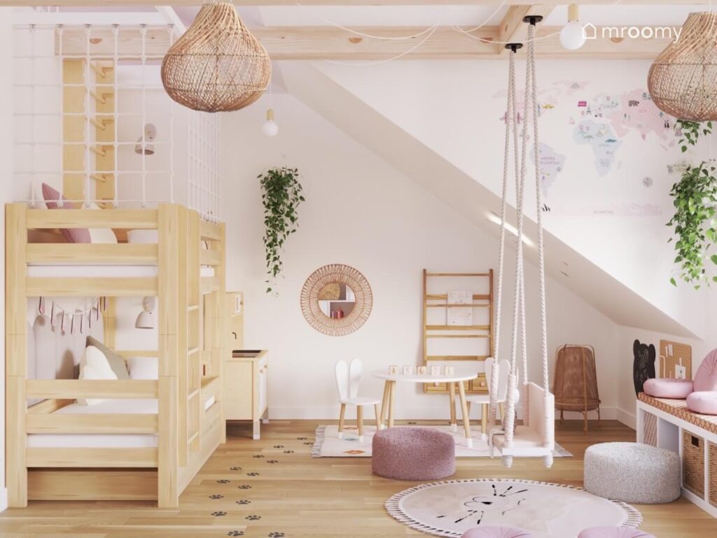 Drewniane łóżko piętrowe biblioteczka huśtawka wisząca i ozdobne kwietniki w jasnym poddaszowym pokoju dziewczynki
