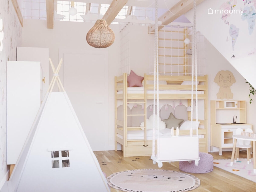 Poddaszowy pokój w delikatnych kolorach a nim namiot tipi huśtawka wisząca oraz drewniane łóżko piętrowe
