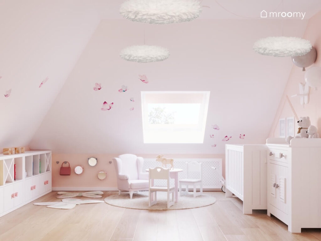 Biały pokój rocznej dziewczynki z białymi meblami motylami na skosach oraz wiszącymi lampami z piór