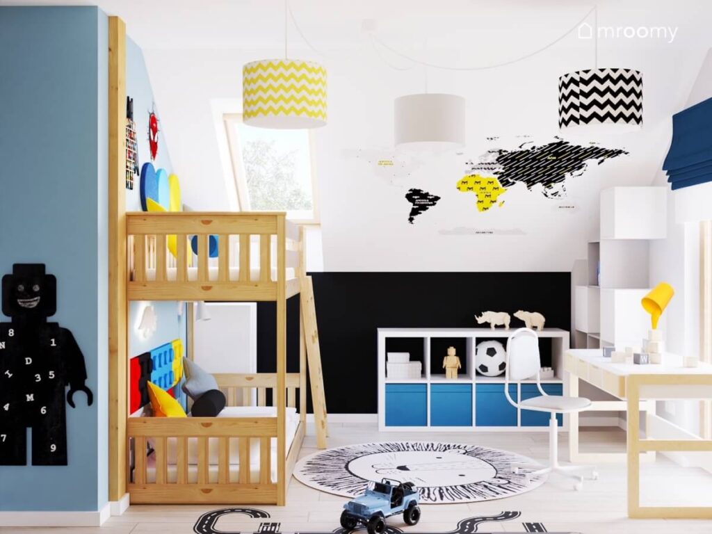 Biało czarno niebieski poddaszowy pokój dla przedszkolaka z drewnianym łóżkiem piętrowym mapą świata na skosie oraz tablicą kredową w kształcie ludzika Lego