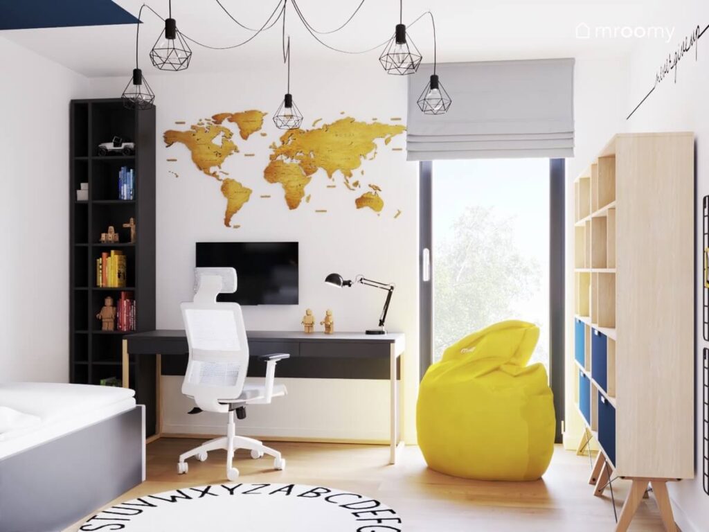 Biały pokój dla chłopca a w nim wysoki czarny regał duże biurko drewniana mapa świata żółta pufa oraz dywan z alfabetem