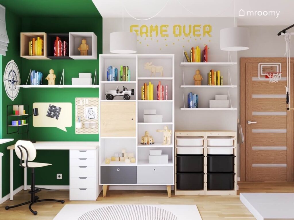 Zielono szaro biały pokój dwóch braci a w nim białe biurko z organizerami półkami i szafkami ściennymi obok duży regał oraz regał z pojemnikami na zabawki