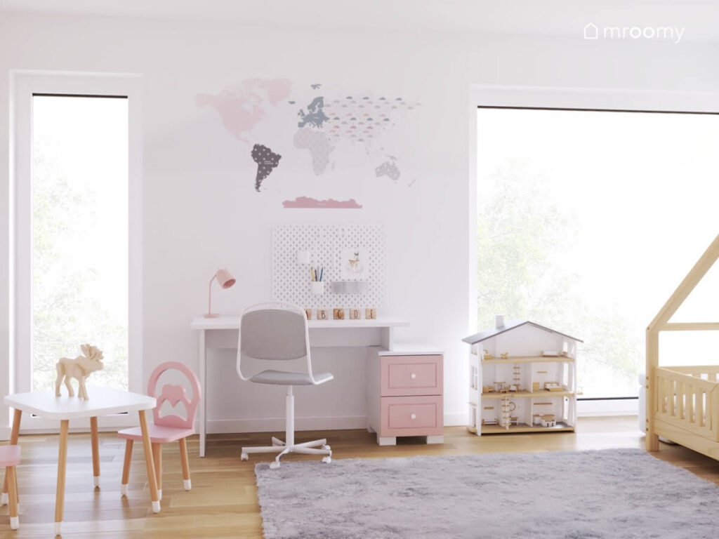 Strefa nauki w pokoju dziewczynki a w niej biurko z szarym krzesłem i niską różową szafą organizer ścienny mapa świata a obok domek dla lalek