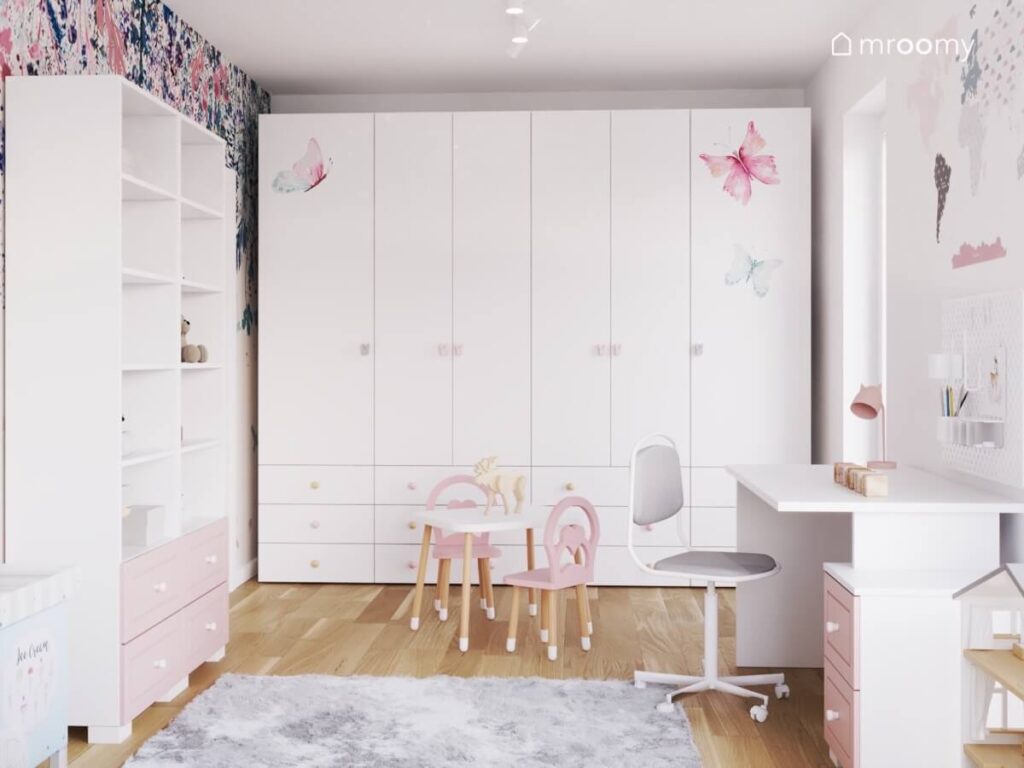 Duża biała szafa w pokoju dziewczynki ozdobiona naklejkami w motyle i gałkami w kształcie królików