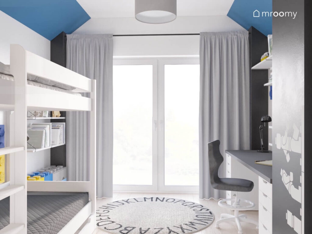 Biało niebieski pokój chłopca w wieku szkolnym a w nim ciemne filary białe łóżko piętrowe i dywan z alfabetem