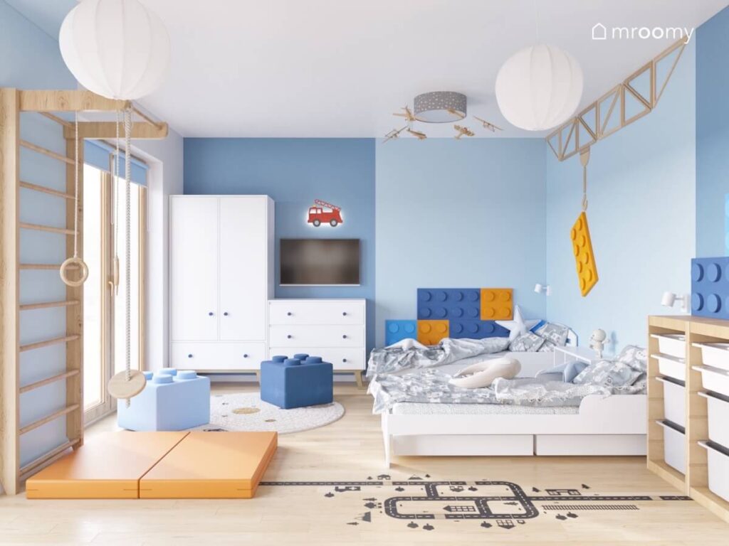 Biało niebieski pokój dla dwóch chłopców a w nim białe meble dwa łóżka oraz dodatki w kształcie klocków