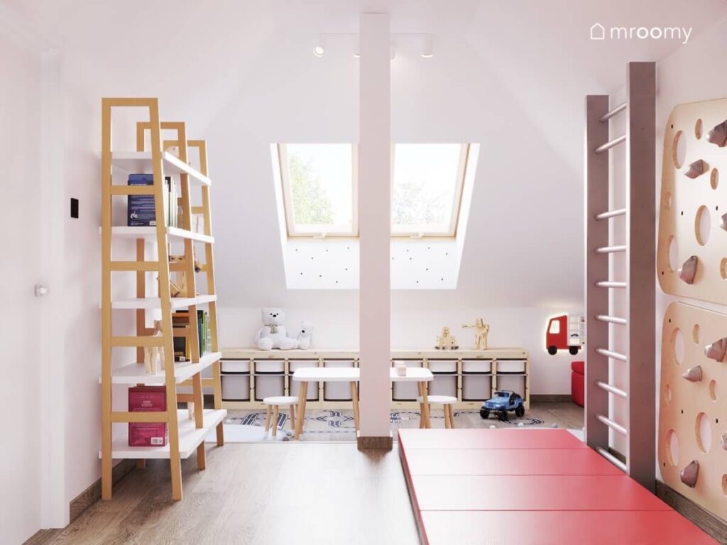 Biały poddaszowy pokój dla dwóch małych chłopców a w nim biało drewniane regały na książki drabinka gimnastyczna ścianka wspinaczkowa i czerwone materace