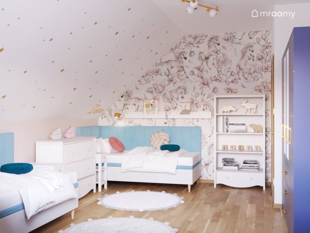 Skos pokryty białymi gwiazdkami oraz piękna tapeta z końmi a także biały regał i białe łóżko uzupełnione niebieskimi panelami w pokoju sióstr