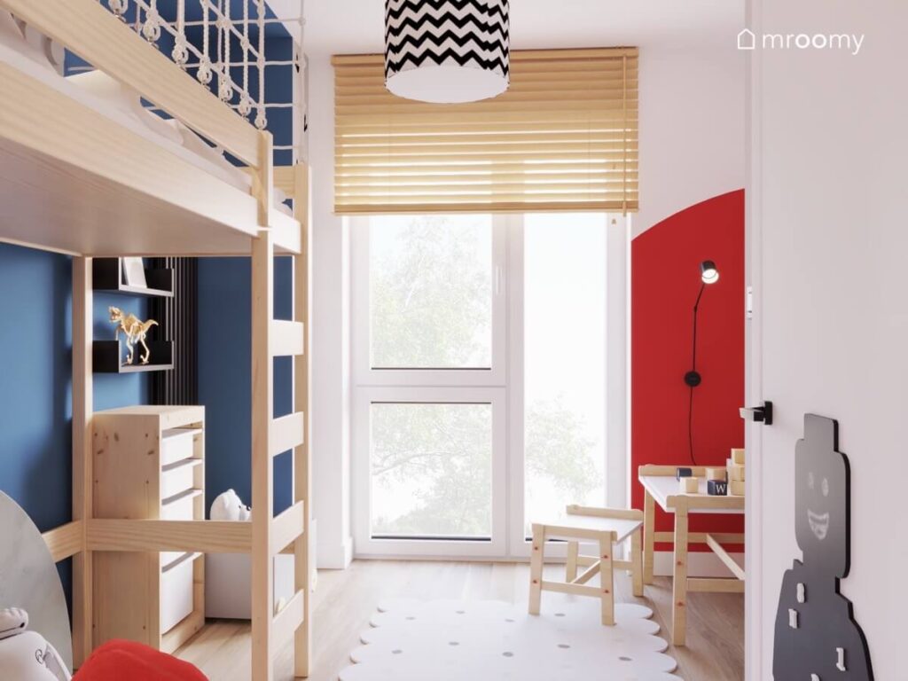 Jasny pokój dla chłopca a w nim drewniane meble czerwone dodatki oraz tablica magnetyczno kredowa w kształcie ludzika Lego