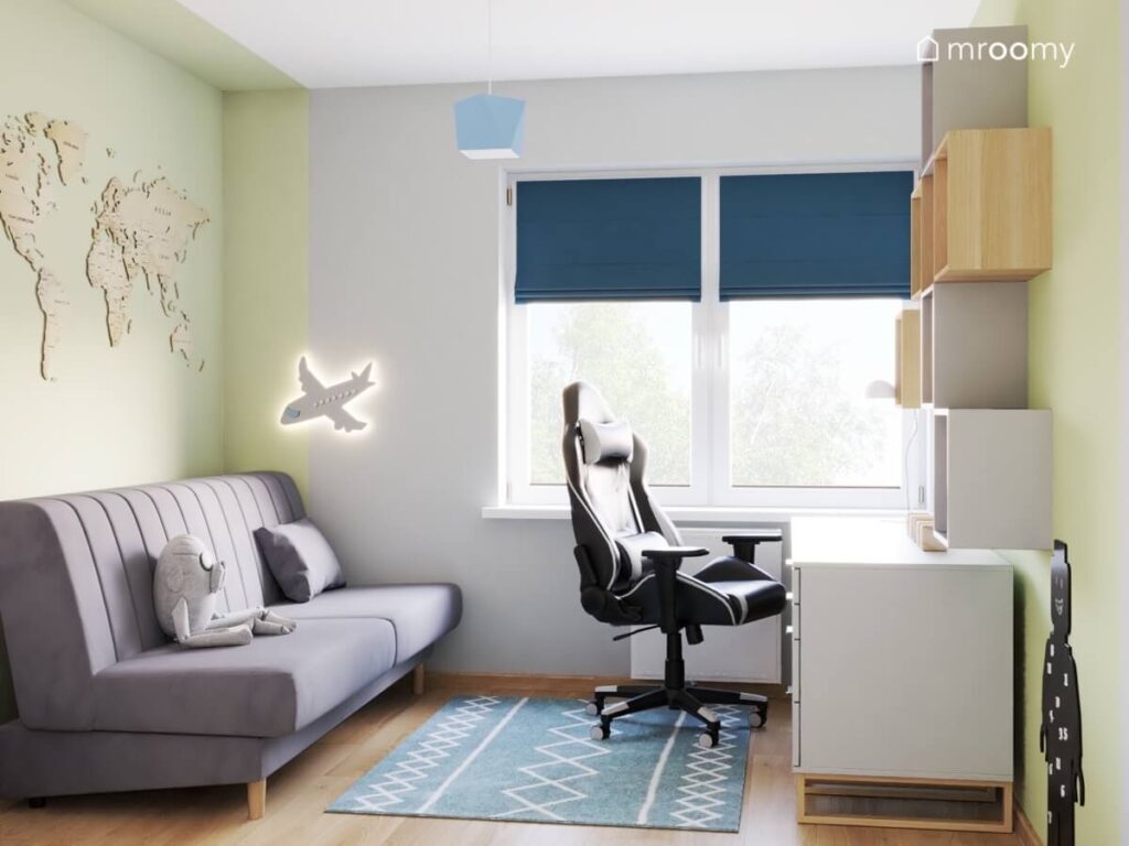 Szaro zielony pokój dla chłopca w wieku szkolnym a w nim szara sofa drewniana mapa świata lampka w kształcie samolotu i niebieski dywan we wzorki na podłodze
