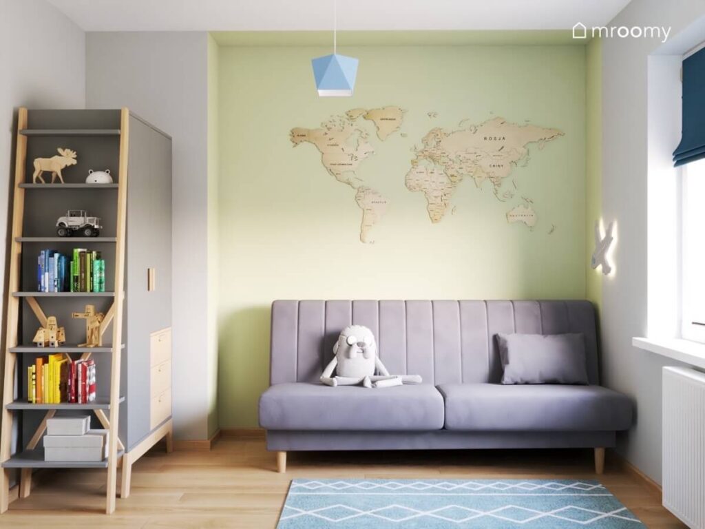 Zielona ściana w pokoju chłopca a na niej drewniana mapa świata a pod spodem szara sofa