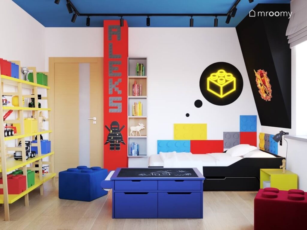 Biały poddaszowy pokój dla chłopca z niebieskim sufitem czerwonym filarem i czarnym skosem a w nim liczne motywy Lego