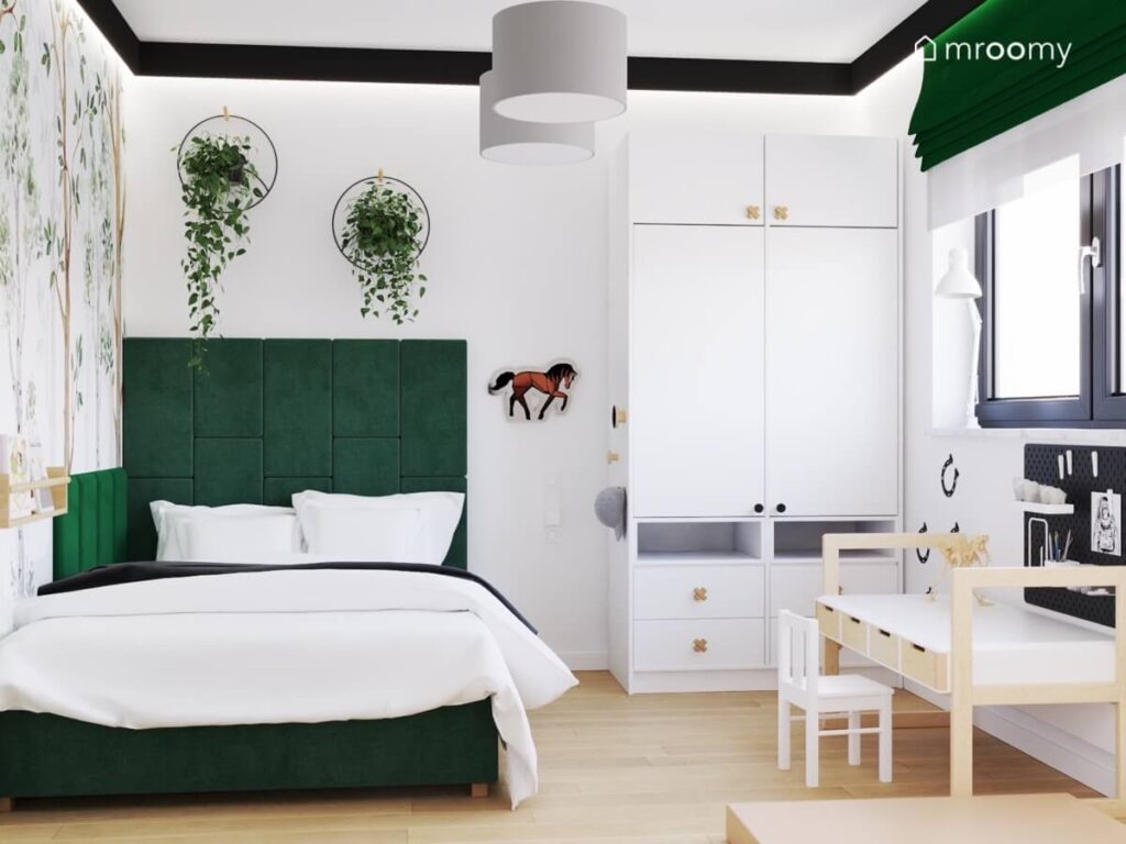 Biały pokój dla kilkuletniego chłopca z białą szafą ciemnozielonym tapicerowanym łóżkiem ozdobnymi kwietnikami oraz ozdobami z motywem konia