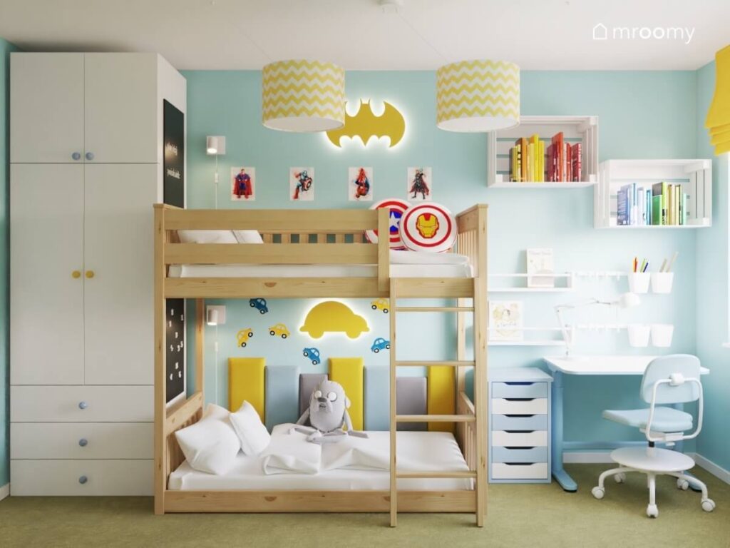 Wysoka biała szafa drewniane łóżko piętrowe oraz strefa nauki w pokoju dla rodzeństwa