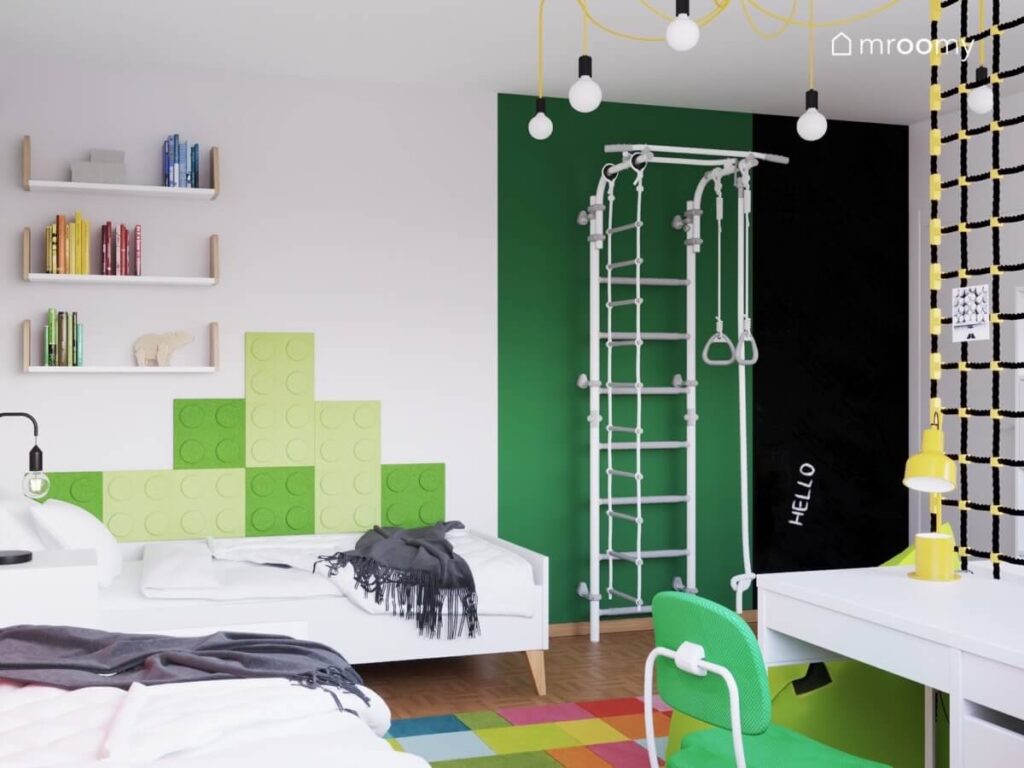 Biało zielony pokój dwóch braci z białymi łóżkami drabinką gimnastyczną zielonymi panelami ściennymi w kształcie klocków oraz powierzchnią kredową