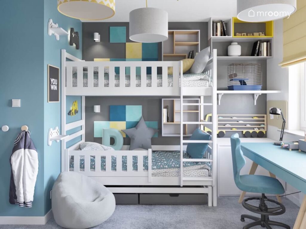 Białe łóżko piętrowe uzupełnione kwadratowymi panelami ściennymi oraz półkami na książki w niebiesko szaro białym pokoju dwóch chłopców