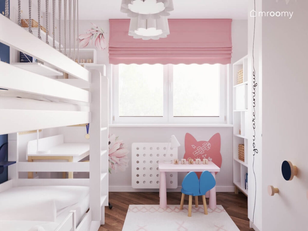 Jasnoszary pokój dla dwóch dziewczynek z białym łóżkiem piętrowym małym stolikiem z niebieskim krzesełkiem różową roletą i naklejkami kwiatami