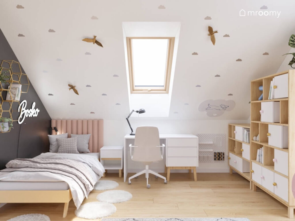 Biały skos w pokoju dla dziewczynki ozdobiony chmurkami oraz drewnianymi ptaszkami a pod spodem łóżko i biurko