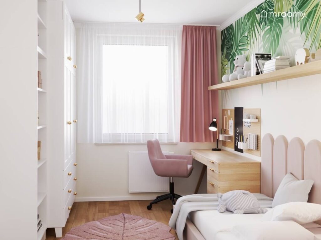 Przytulny pokój dla dziewczynki z białymi meblami drewnianym biurkiem różowymi dodatkami oraz dywanem liściem