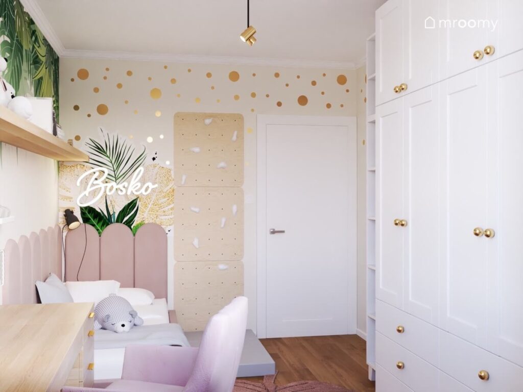 Ściana w złote kropki a na niej panele wspinaczkowe ledon oraz naklejka w liście a obok duża biała szafa w pokoju dla dziewczynki