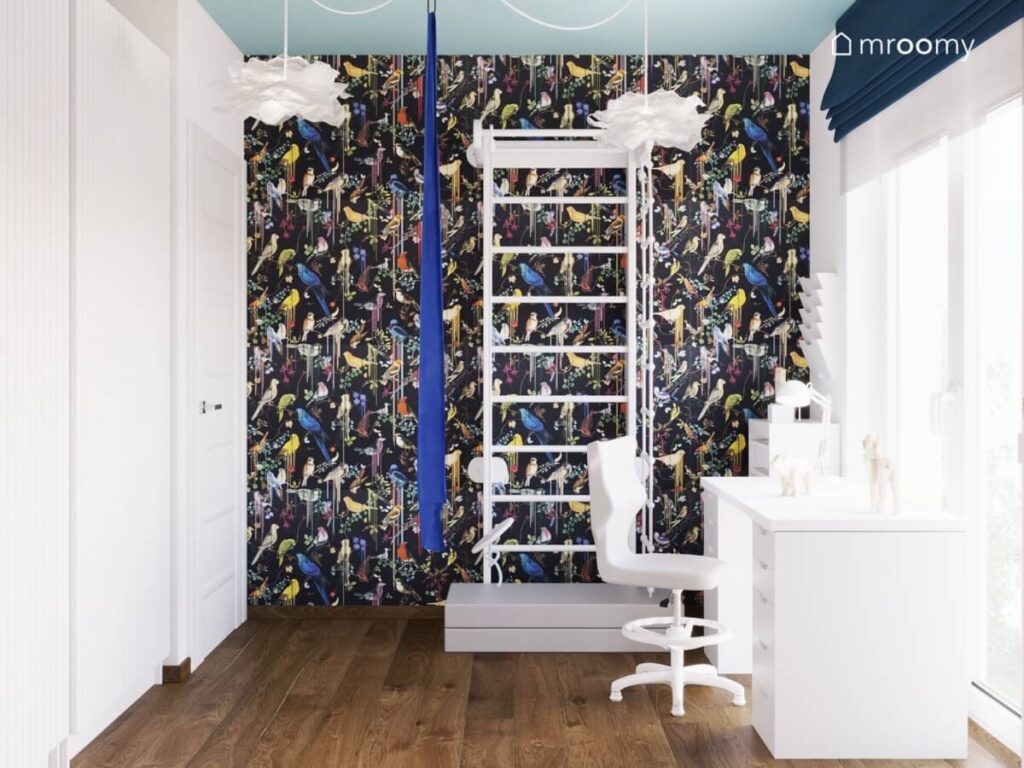 Ściana w pokoju sześciolatki pokryta kolorową tapetą w ptaki a na niej drabinka gimnastyczna z materacem