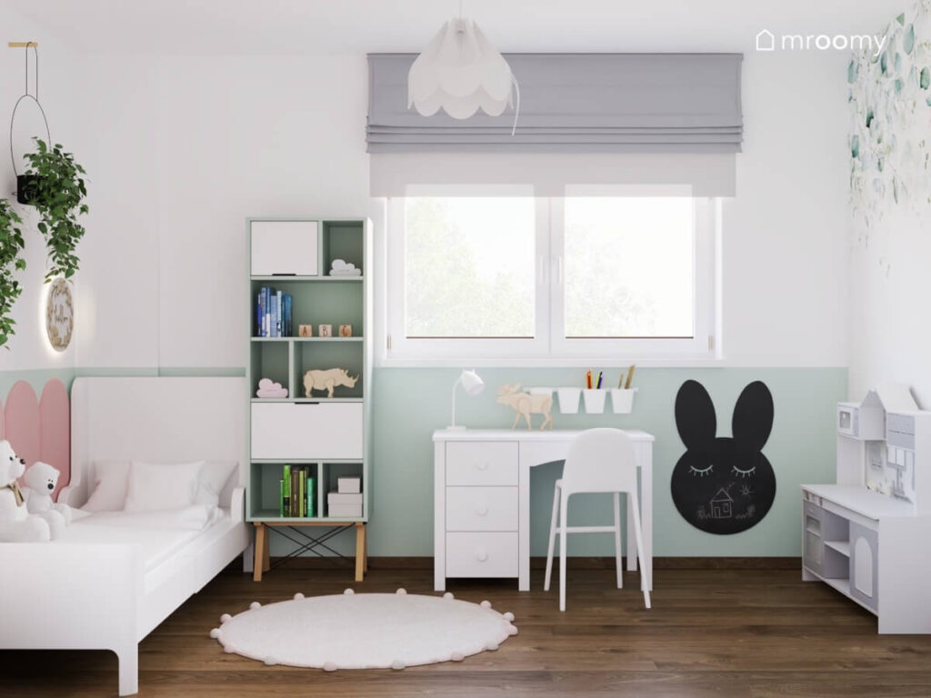 Jasny pokój dla dziewczynki o białych i jasnozielonych ścianach a w nim białe łóżko regał biurko oraz tablica kredowa w kształcie królika