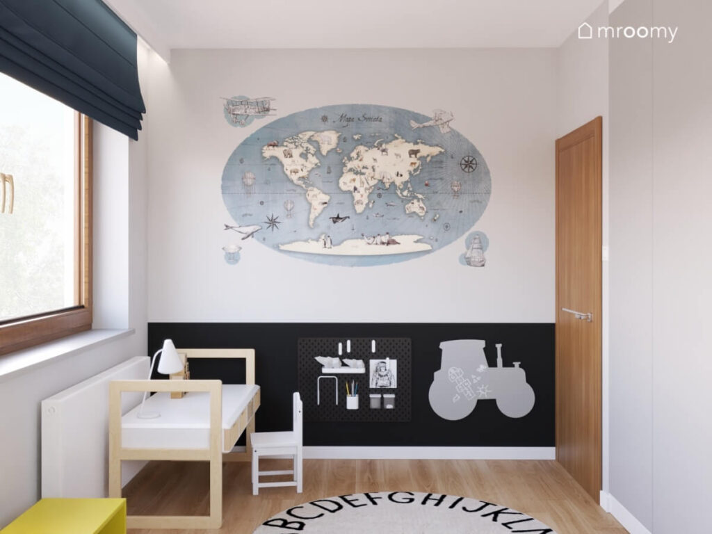 Biało czarna ściana w pokoju chłopca a na niej duża mapa świata organizer oraz tablica kredowa traktor