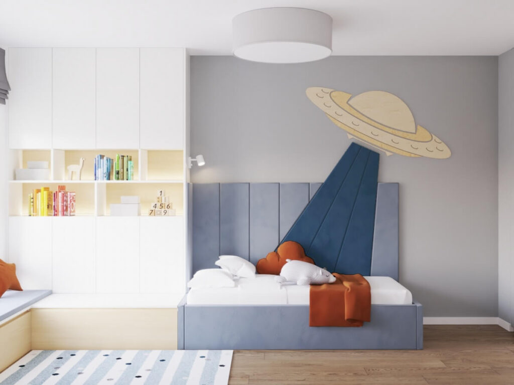 Niebieskie tapicerowane łóżko w pokoju dla chłopca obok szafa z półkami na ścianie statek UFO  ze sklejki a na suficie plafon