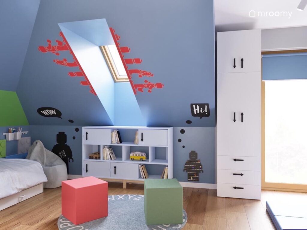 Niebieski skos w pokoju dla chłopca a na nim naklejki ścienne w ludzikami Lego oraz tablica kredowa ludzika na na podłodze sześcienne pufy oraz dywan z alfabetem