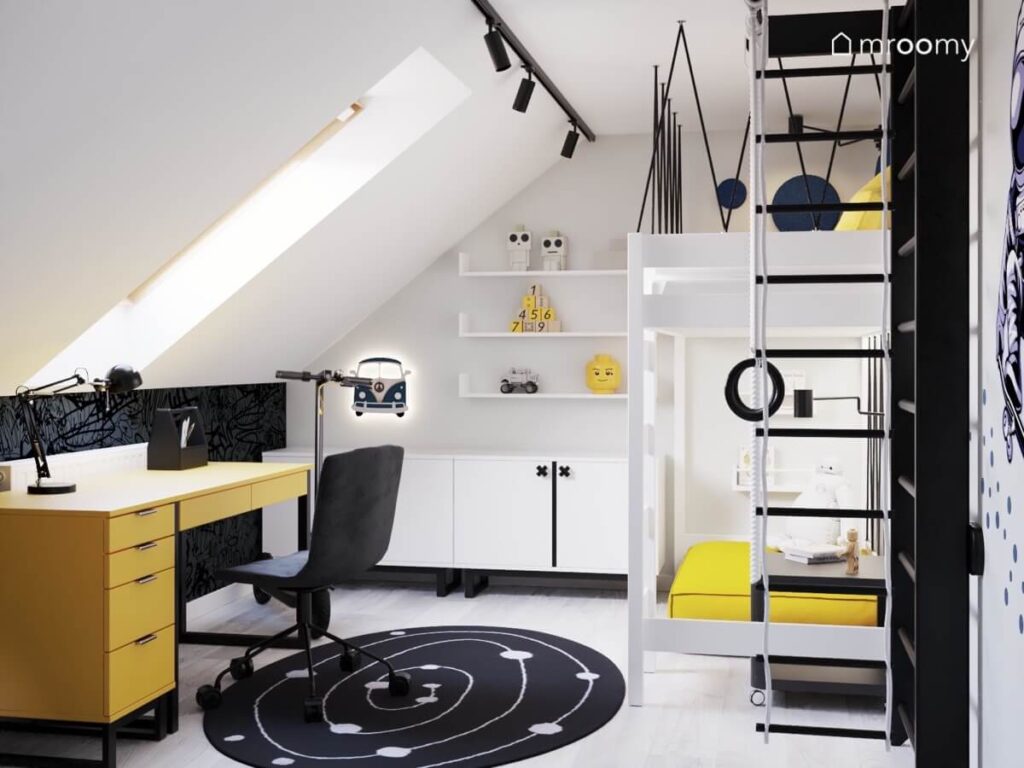 Poddaszowy pokój dla chłopca z białymi szafkami i antresolą żółtym biurkiem oraz czarną drabinką gimnastyczną