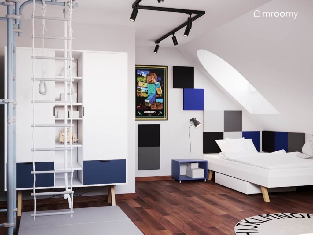 Biały poddaszowy pokój dla chłopca a w nim biało granatowe meble drabinka gimnastyczna oraz plakat z motywem Minecraft