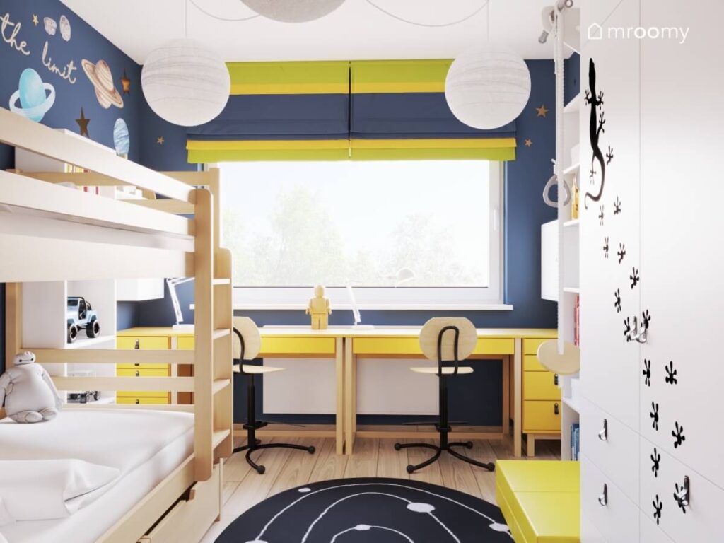 Granatowy pokój dla dwóch chłopców z żółtymi biurkami drewnianym łóżkiem piętrowym i kosmicznym dywanem