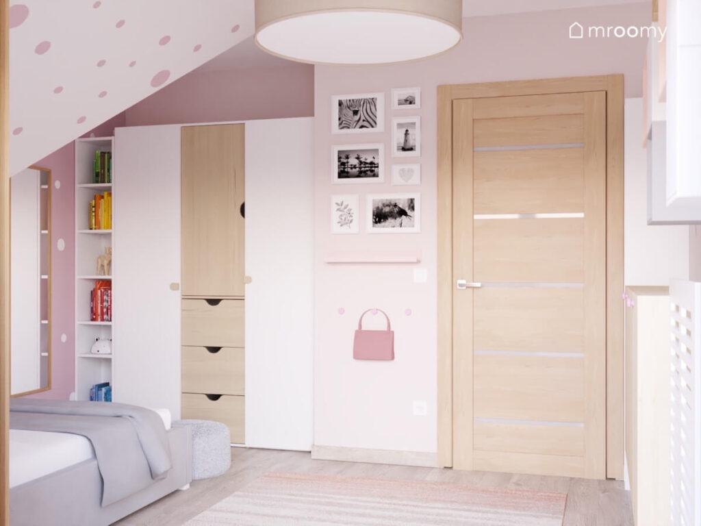 Biało różowy poddaszowy pokój dla dziewczynki w wieku szkolnym a w nim biało drewniana szafa regał i zdjęcia w ramkach na ścianie