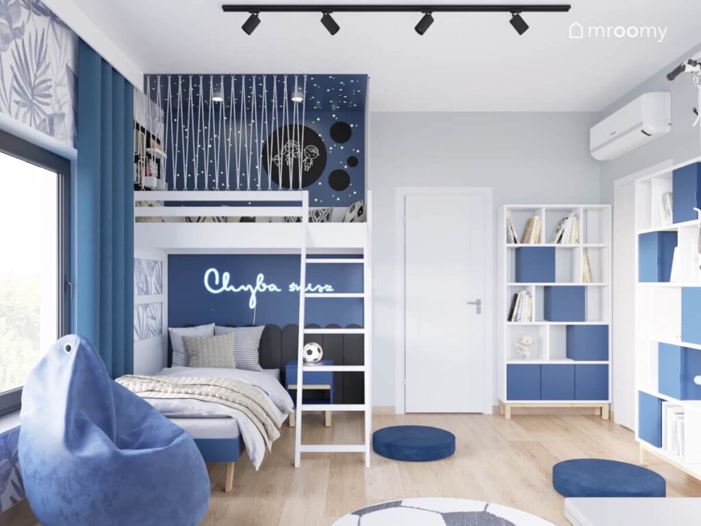 Szary pokój dla dziewczynki z niebieska strefą spania z antresolą i łóżkiem pod spodem oraz biało niebieskim regałem i kilkoma pufami