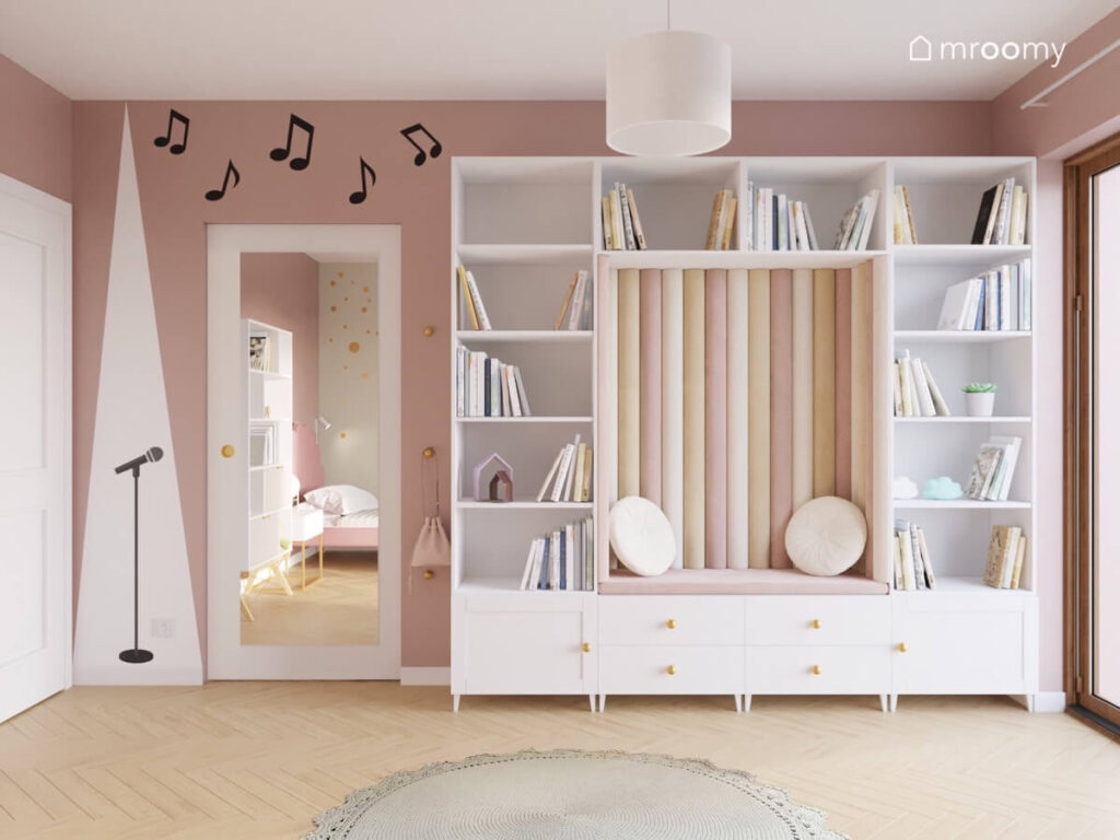 Różowa ściana w pokoju dziewczynki a na niej naklejka mikrofon i nutki oraz duża szafa z przytulnym kącikiem pośrodku