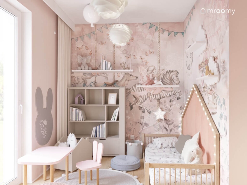 Przytulny pokój dla malutkiej dziewczynki a w nim drewniane łóżko domek półki ścienne regał stolik z krzesełkami w kształcie króliczych uszu a na suficie ozdobne lampy