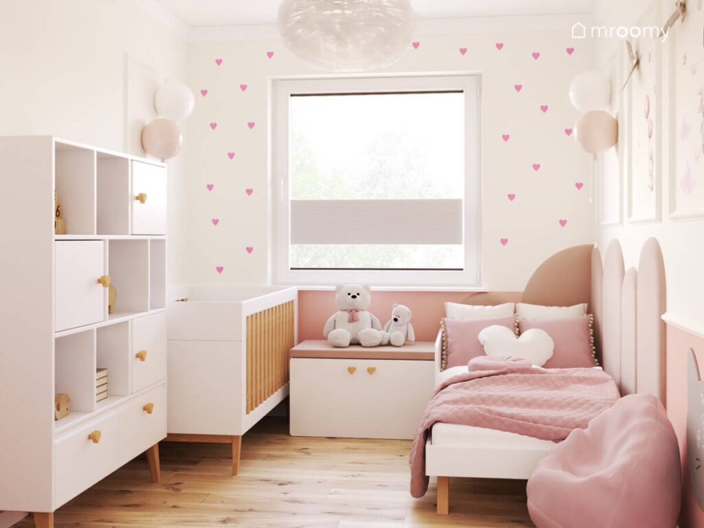 Jasny pokój dla dwóch dziewczynek z białymi meblami z drewnianymi elementami oraz kinkietami balonami na ścianie