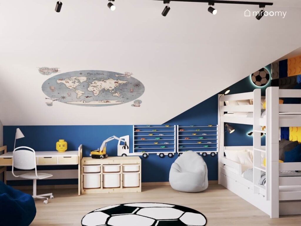 Biało niebieski pokój dla dwóch chłopców z biało drewnianymi meblami mapą świata na skosie oraz piłkarskimi motywami